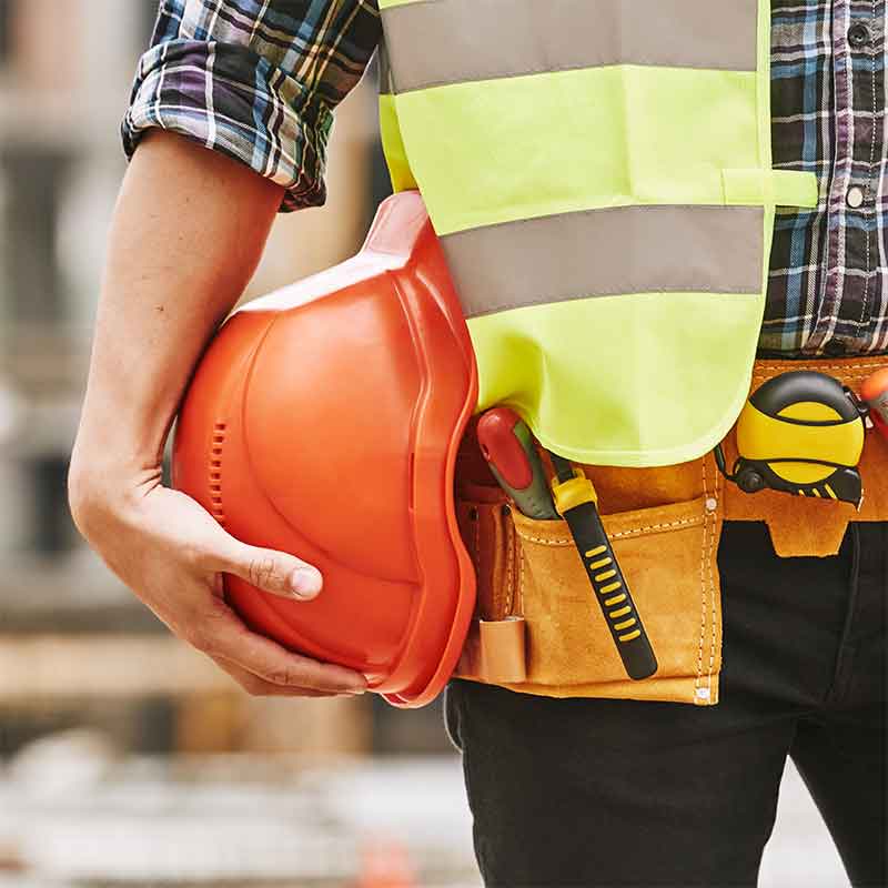 Construction worker holding a hard hat that should also have hearing protection while working.