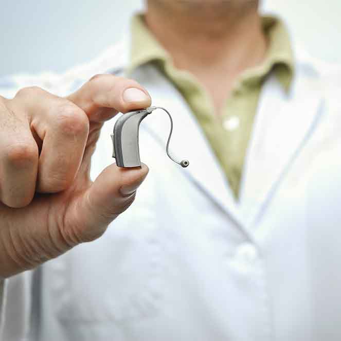Hearing Aid specialist holding a hearing aid that has just been repaired.
